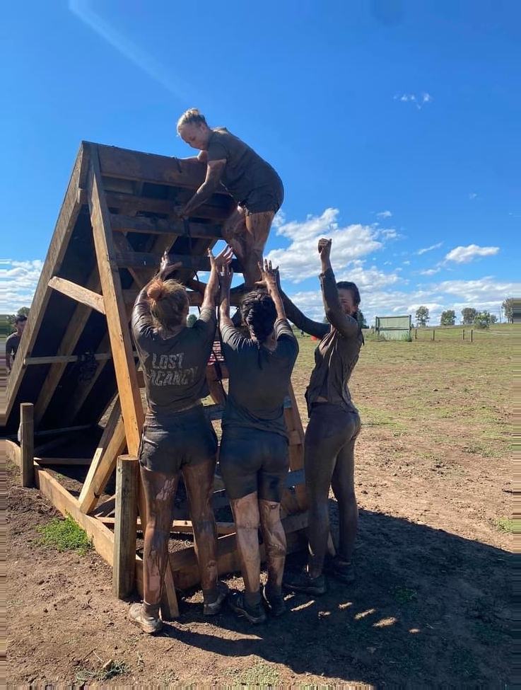 Young people building and climbing a timber structure during a youth program challenge